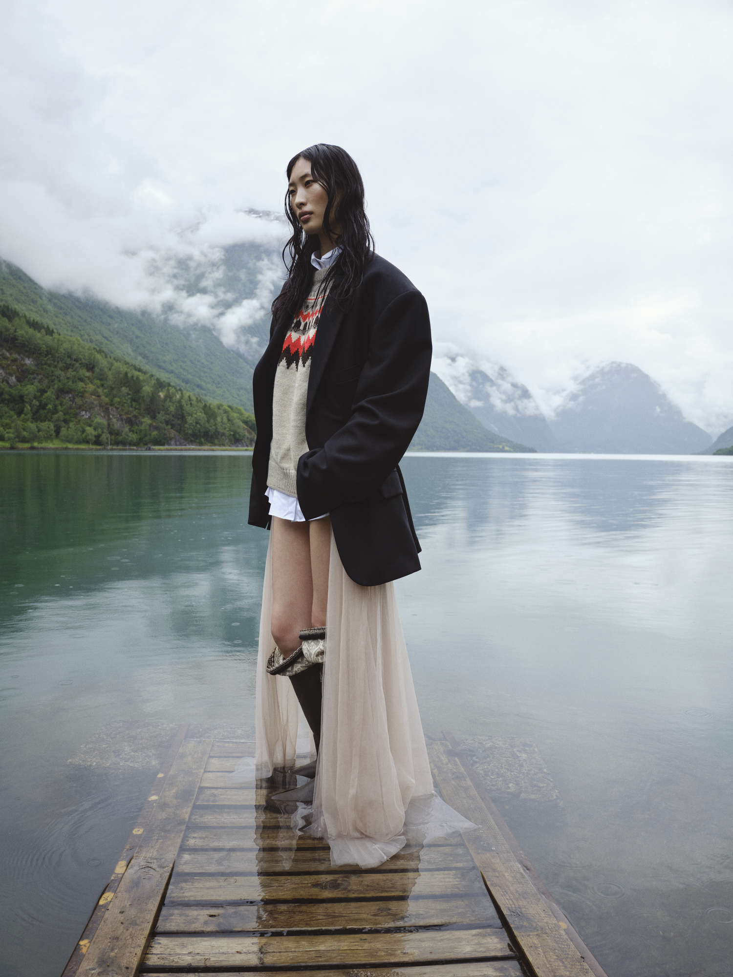 female model wearing knitted sweater from Dale of Norway standing on a boat ramp in the fjords