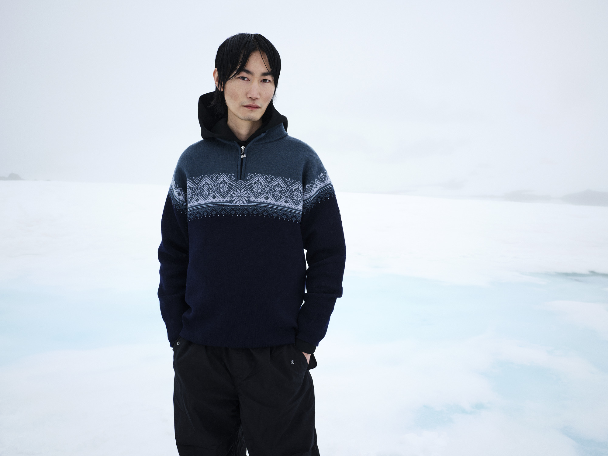Male model wearing wool jumper standing in a snowy background