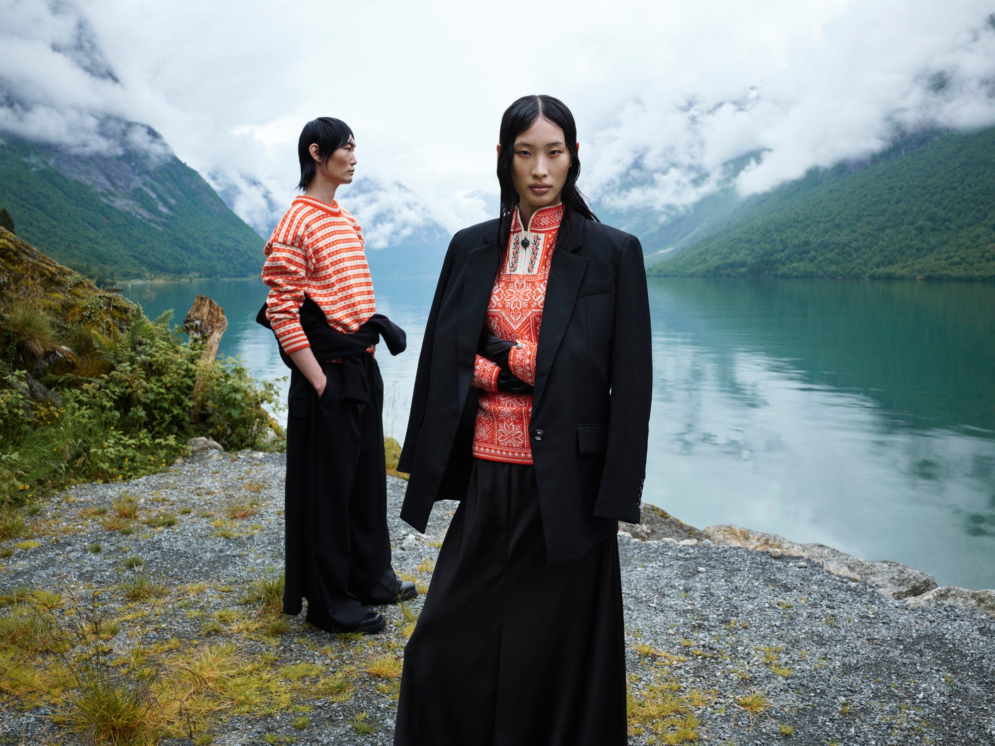 Two female models standing by the Norwegian fjord wearing wool sweaters
