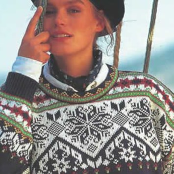 A woman looks toward the camera, wearing the Olympic sweater from the 1992 Summer Olympics in Barcelona, featuring a black and white pattern with green and red details